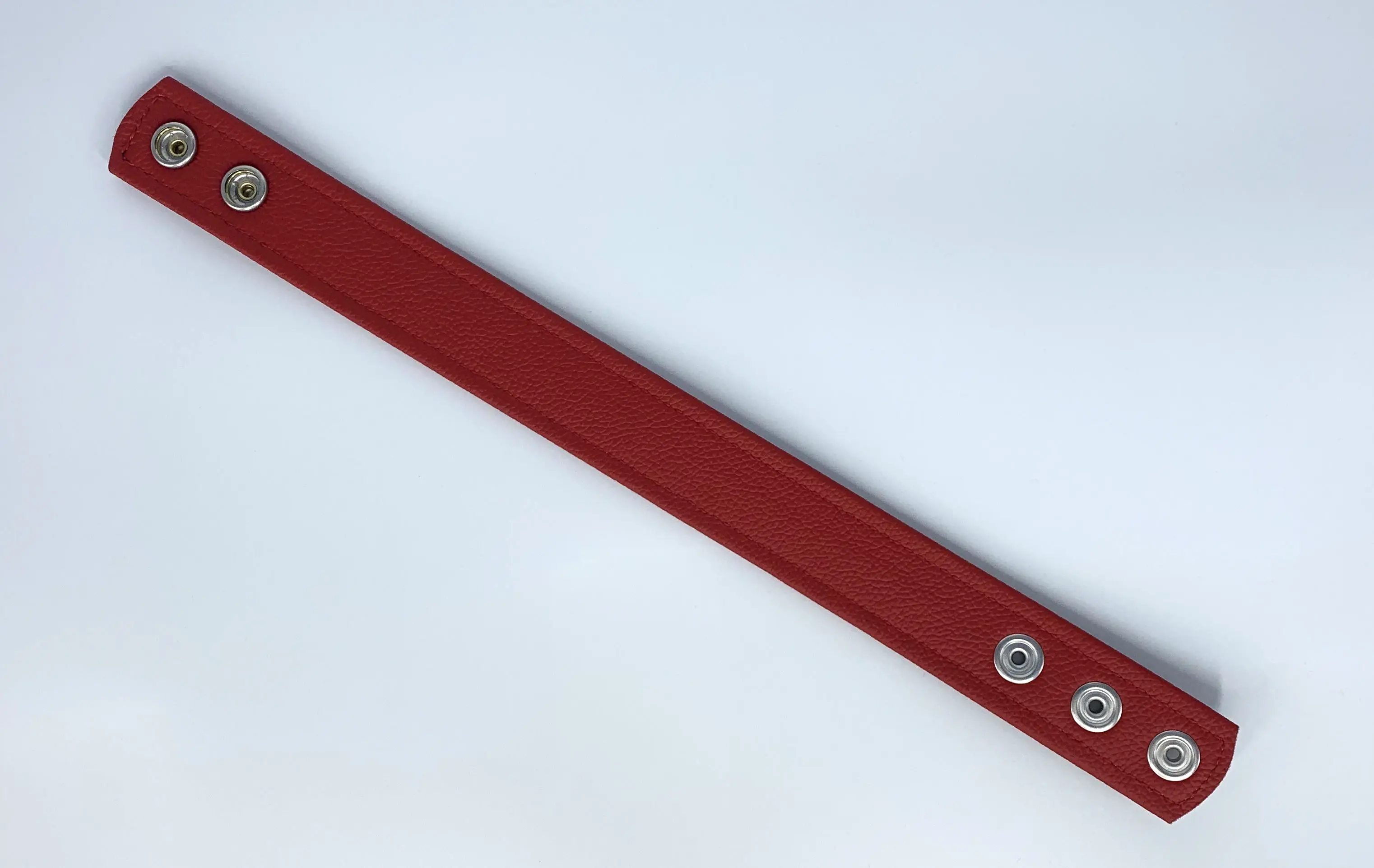Rote Innenseite des Leder-Oberarmbands mit Druckknöpfen zur Weitenverstellung