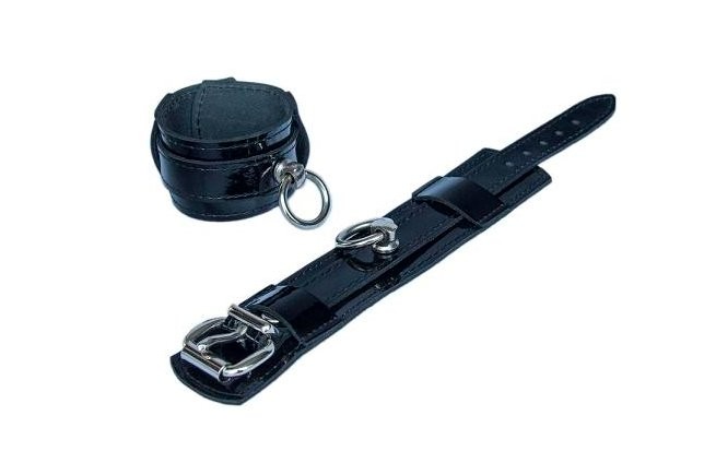 Freisteller von Handfesseln aus Lackleder mit Ring der O in schwarz