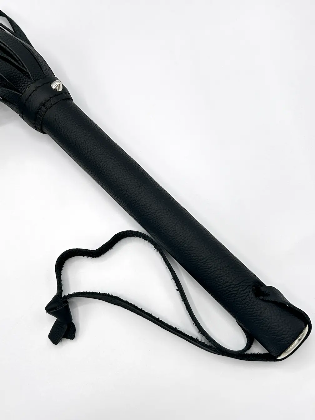 Detailaufnahme Griff des schwarzen Leder-Floggers mit Metallkappe und Handschlaufe