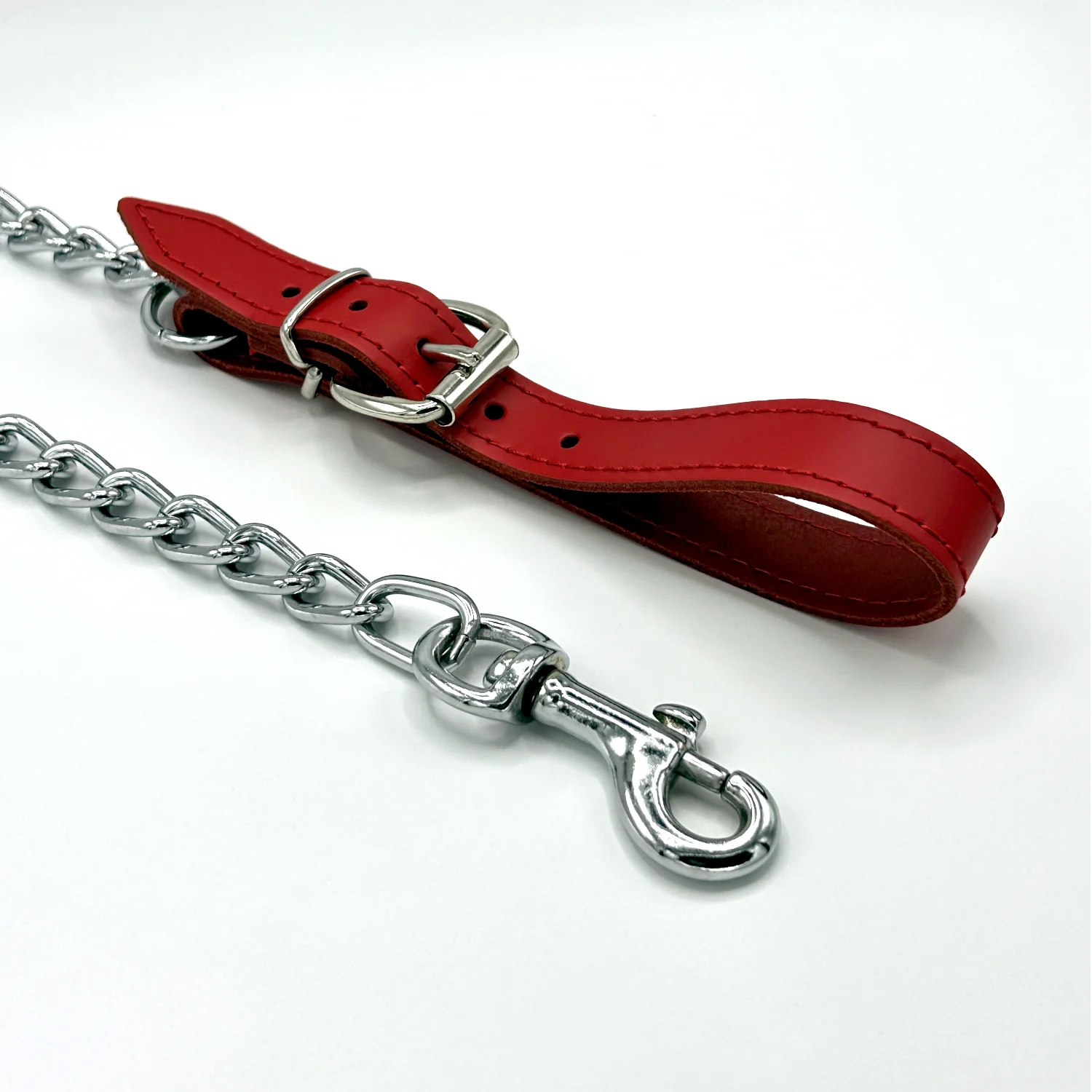 Unverwüstliche rote Führungsleine aus Leder und Kette mit zu öffnender Handschlaufe, Schnalle und Bolzenkarabiner auf weißem Hintergrund.